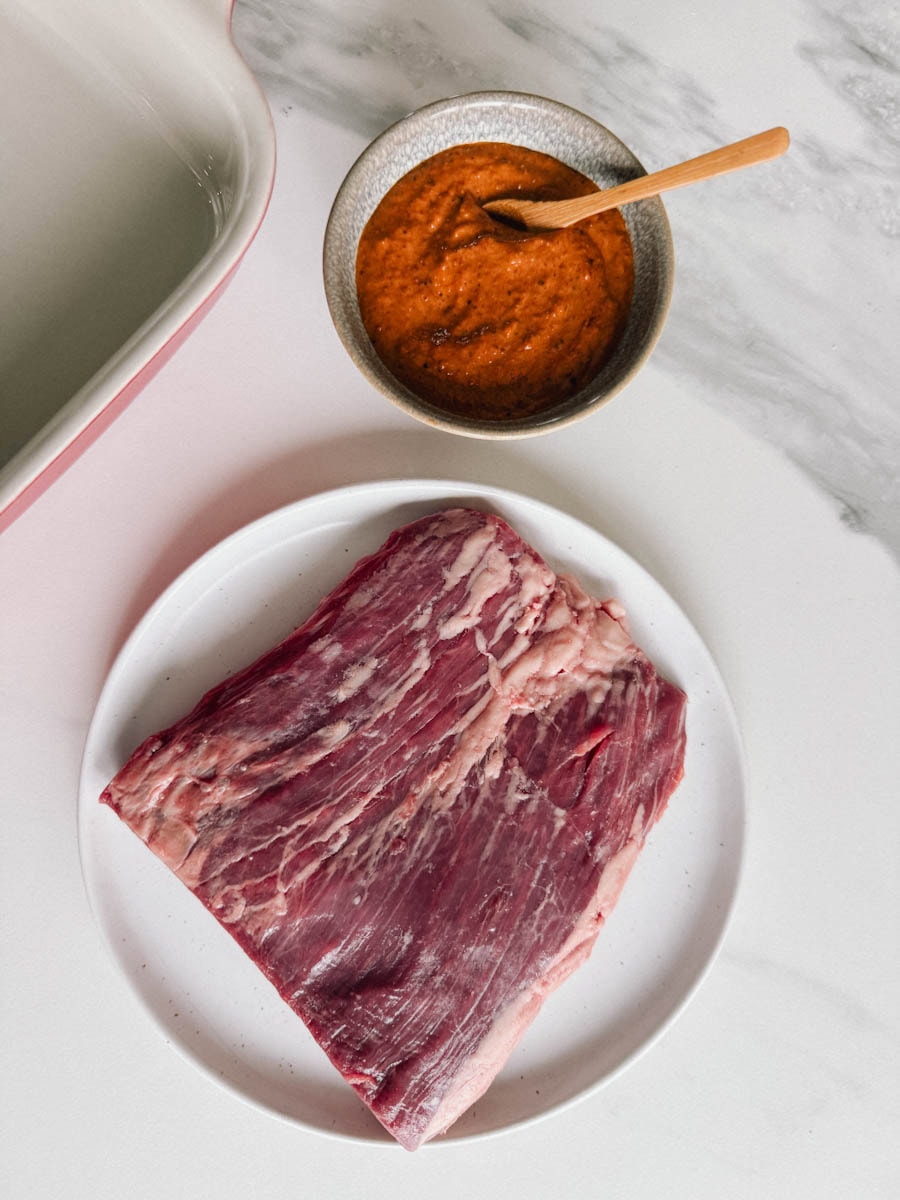 steak de flanc dans une assiette blanche avec sauce et mariande chipotle dans un bol