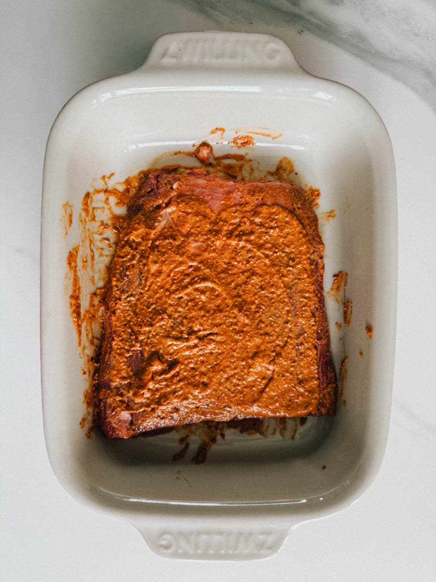 steak qui marine avec sauce rouge chipotle dans un plat à gratin