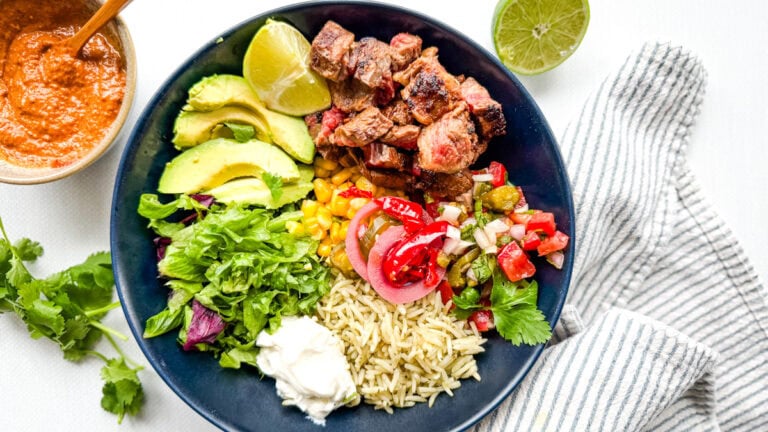 bol steak chipotle avec riz, légumes, pot de sauce chipotle, citron vert sur comptoir blanc