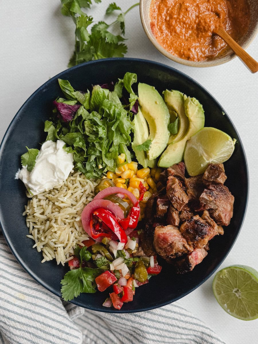 bol style chipotle avec riz, légume, steak en dés, avocat avec pot de sauce chipotle à côté