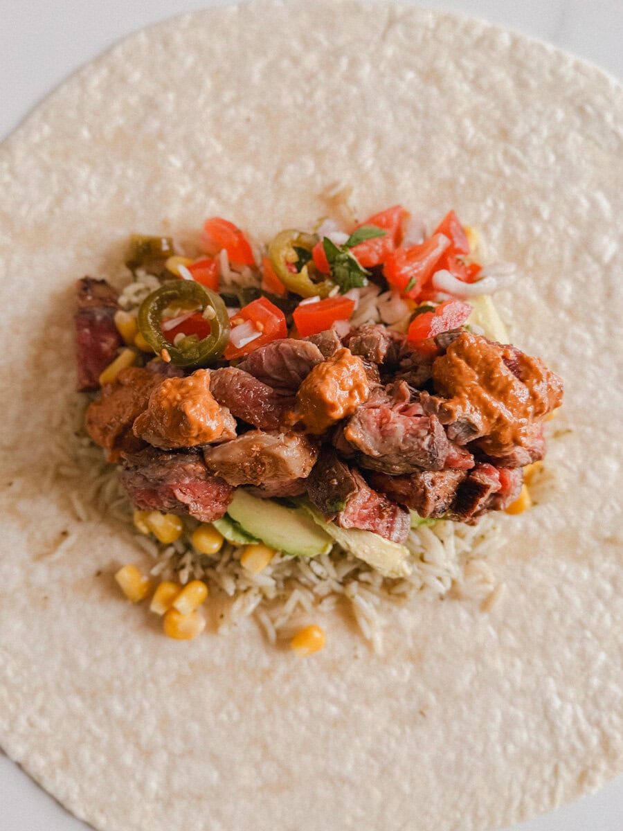 burrito ouvert avec farce de steak chipotle, sauce, riz, avocat et tomates
