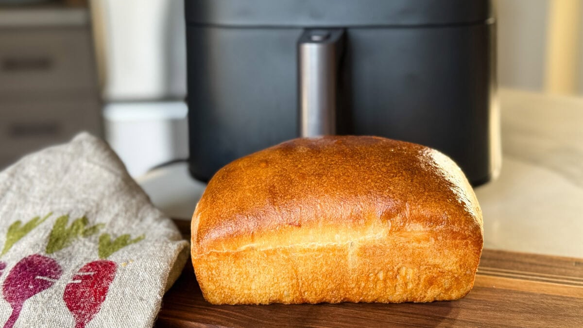 pain au levain sur planche de bois devant un air fryer gris foncé