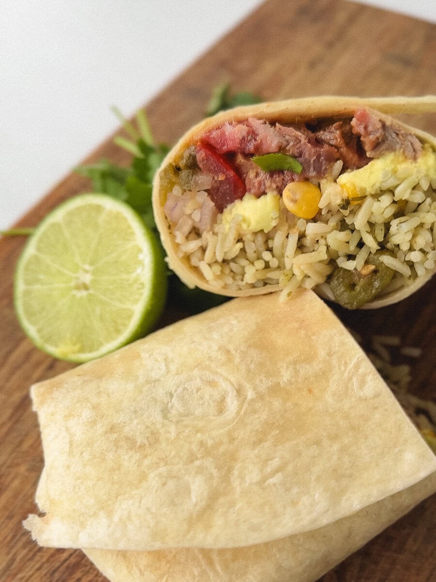burrito au steak chipotle sur planche de bois avec citron vert
