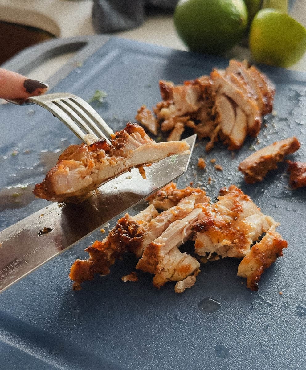main qui coupe du poulet grillé au couteau