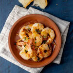 crevettes grillées dans un plat en terre cuite avec miche de pain