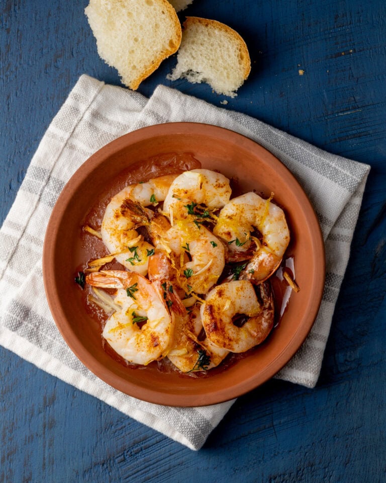 crevettes grillées dans un plat en terre cuite avec miche de pain