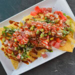 assiette rectangulaire blanche remplie de nachos poke, thon, chips de wonton, sauce